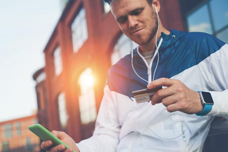 Man with credit card and mobile phone sitting on the street, web money and online payment Man with credit card and mobile phone sitting on the street, web money and online payment