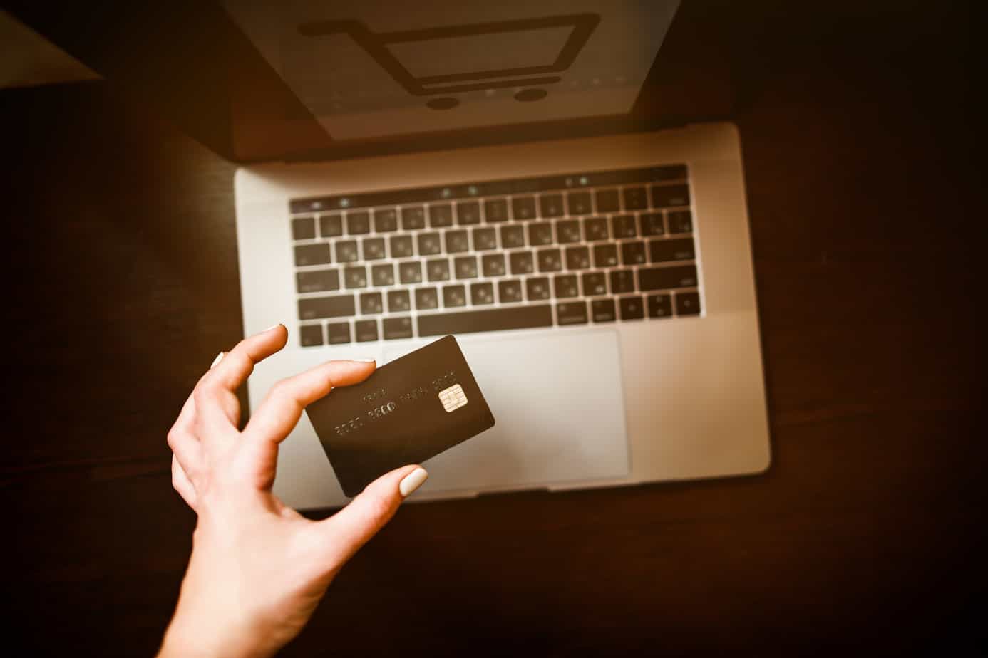 hand-with-credit-card-above-laptop-keyboard-179016423 hand-with-credit-card-above-laptop-keyboard-179016423