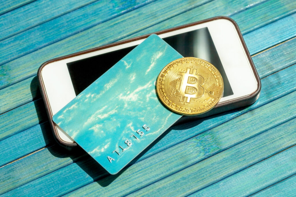 bitcoin gold coin and a gift card credit card laying on top of a modern smartphone screen btc blockchain payments mobile 216994757