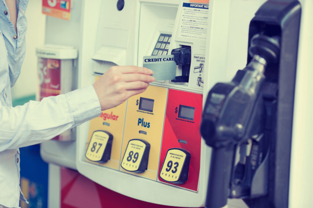 woman hand swiping credit card at gas pump station 50050949