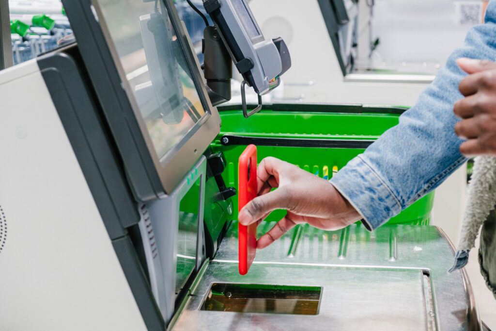 a close up of an african man x27 s hand paying at a grocery supermarket checkout with a contactless payment using a mobile 220100705